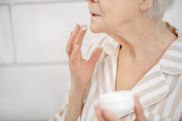 Imagen de cerca de una mujer con un frasco de crema en las manos — Foto de Stock