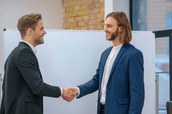 Dos hombres sonrientes en trajes de negocios dándose la mano — Foto de Stock