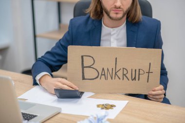 Ofisinde afişi olan uzun saçlı bir adam var.