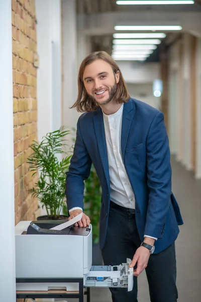 Glimlachende jongeman in de buurt van gadget in kantoor gang — Stockfoto