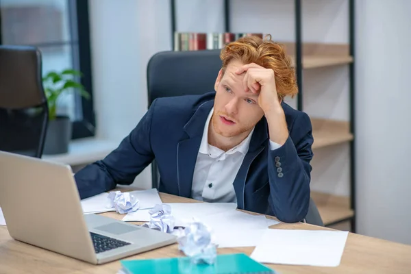 Müder junger Mann arbeitet im Büro am Laptop — Stockfoto