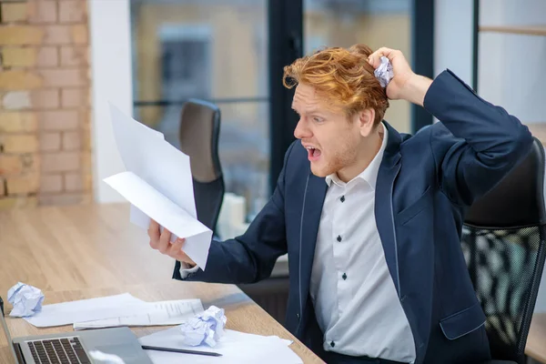 Überraschter Mann mit zerknüllten Dokumenten am Arbeitsplatz — Stockfoto