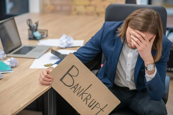 İflas posterli, üzgün genç bir adam.