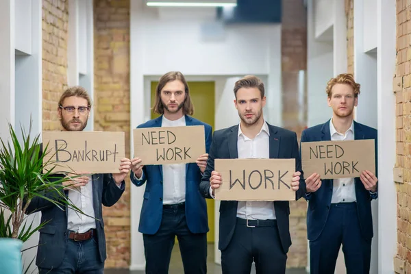 Ellerinde pankartlarla dört üzgün adam.