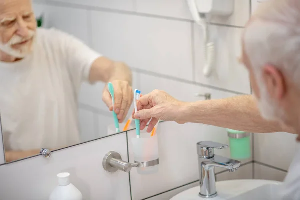 Uomo dai capelli grigi in camicia bianca che lava in bagno — Foto Stock