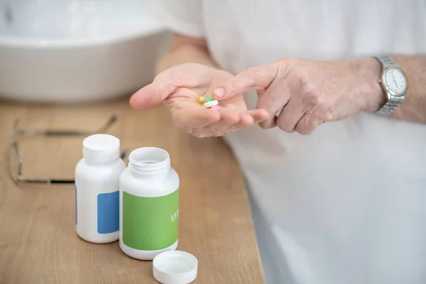 Man holding pills in hands getting ready to take them — Stock Photo, Image