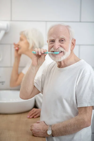 Pareja mayor cepillándose los dientes juntos en el baño — Foto de Stock