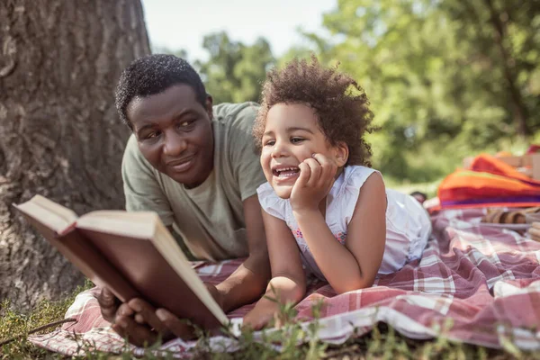 Hombre afroamericano y su lindo niño leyendo un libro juntos —  Fotos de Stock