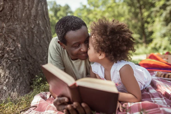 Αφροαμερικάνος και το χαριτωμένο παιδί του διαβάζουν ένα βιβλίο μαζί. — Φωτογραφία Αρχείου