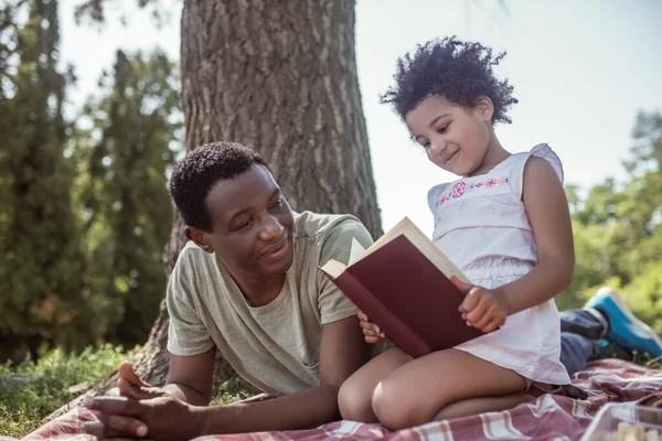 Hombre afroamericano y su hijo leyendo un libro juntos —  Fotos de Stock