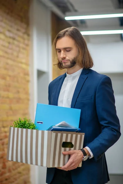 Sad man with personal belongings in office corridor