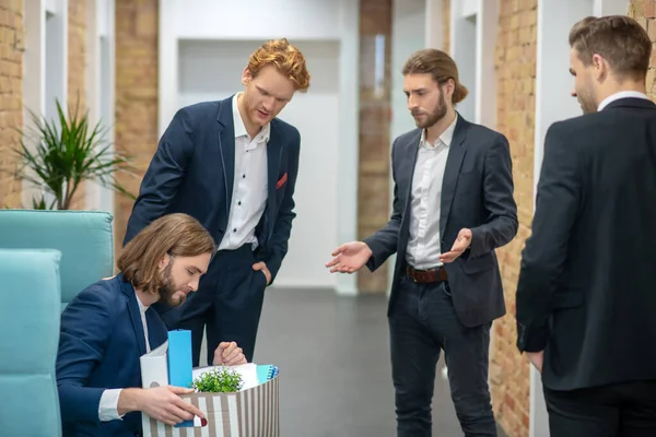 Man sitter med låda och tre kollegor står — Stockfoto