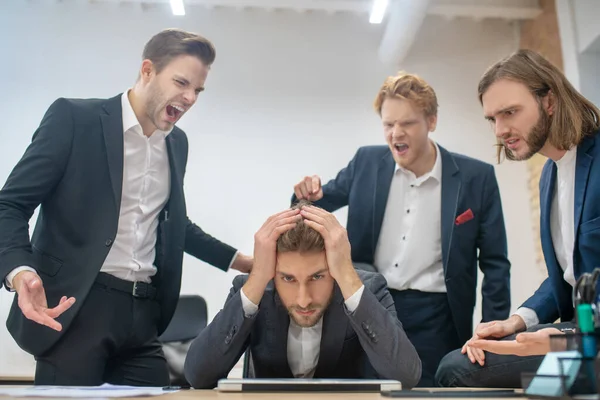 Der Mann am Tisch und seine Kollegen beschuldigen ihn — Stockfoto