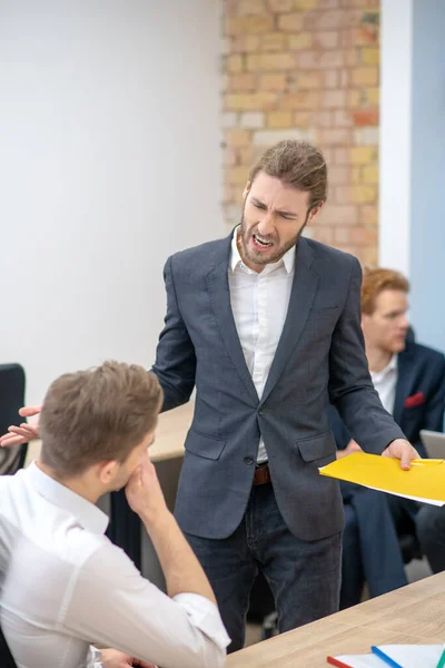 Nervös man med dokument skriker på anställd — Stockfoto