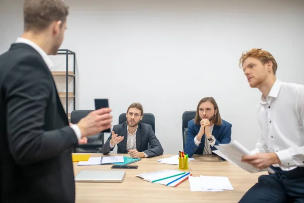 Allvarliga män vid bordet lyssnar uppmärksamt på sin kollega — Stockfoto