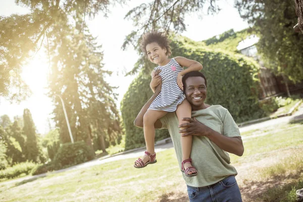 Uomo afroamericano trascorrere del tempo nel parco con sua figlia e cercando felice — Foto Stock