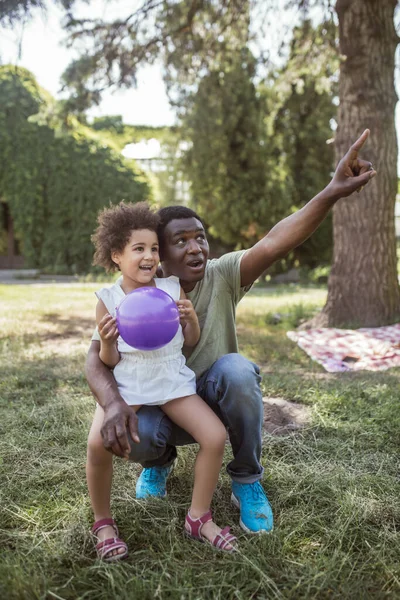 Hombre afroamericano mostrando algo a su hija en el parque —  Fotos de Stock