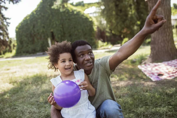 Αφροαμερικάνος δείχνει κάτι στην κόρη του στο πάρκο. — Φωτογραφία Αρχείου