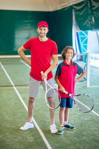 赤い帽子のコーチと少年はテニスをする時間を過ごす — ストック写真
