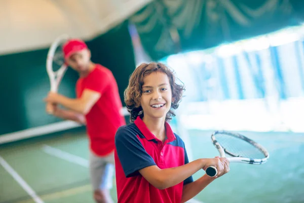 Trainer mit roter Mütze und ein Junge beim Tennisspielen — Stockfoto