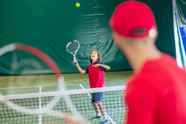 Bild eines Mannes mit roter Mütze, der mit einem Jungen Tennis spielt — Stockfoto