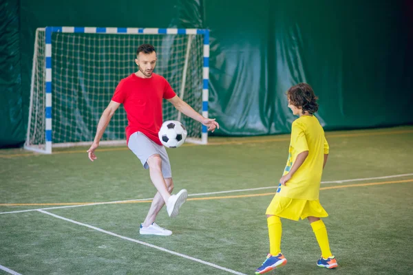 Niño en uniforme amarillo jugando al fútbol con su entrenador — Foto de Stock