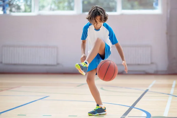 Schuljunge in Sportbekleidung trainiert seine Basketballkünste in einem Fitnessstudio — Stockfoto