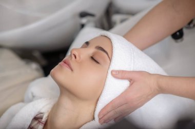 Saç stilisti müşterilerinin saçlarını havluyla kurutuyor.