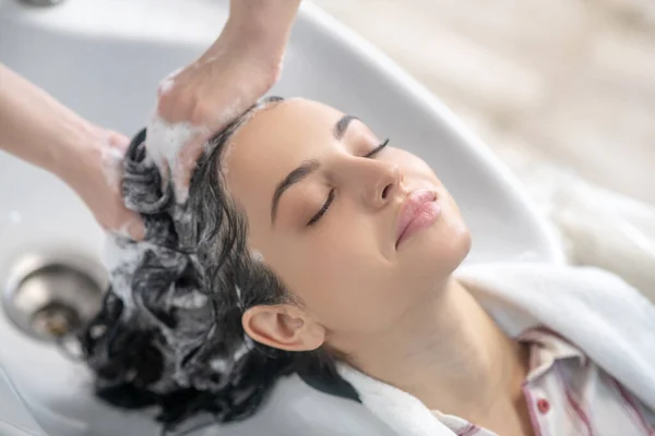 Woman looking relaxed while hair stylist washing her hair