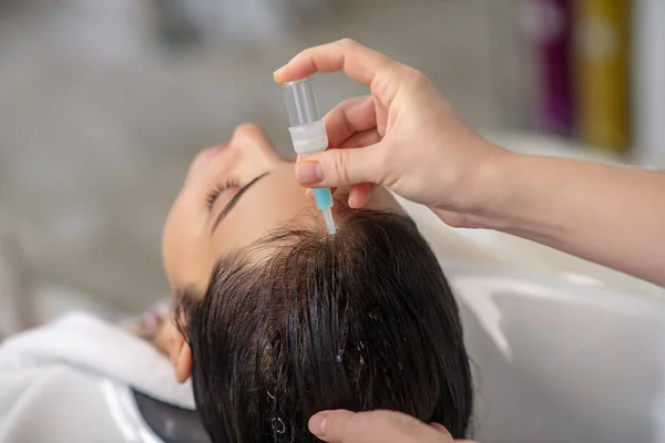 Hair stylist applying keratin on her clients hair