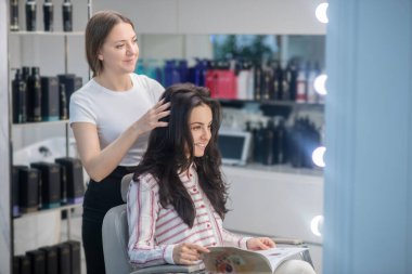 Koyu saçlı kadın kuaförde vakit geçiriyor.