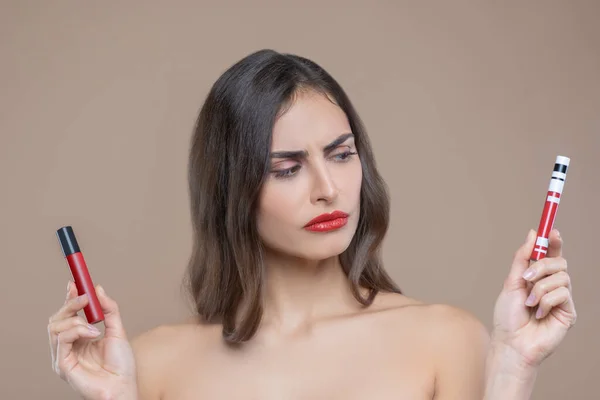 Серьезная женщина с красными блесками для губ в руках — стоковое фото