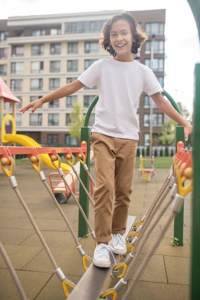 Leuke jongen in een wit tshirt spelen op een speelplaats — Stockfoto