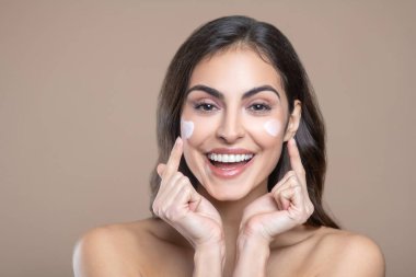 Çıplak omuzlu, yanaklarını gösteren bir kadın.