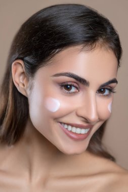 Yanağında krema olan güzel bir kadının yakın plan yüzü.