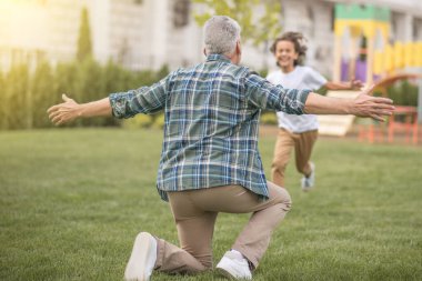 Çocuk babasına koşuyor ve mutlu görünüyor.