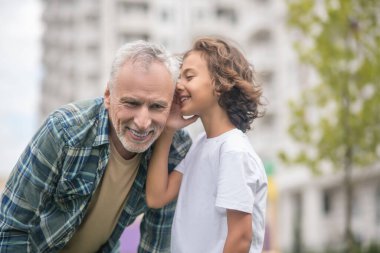 Koyu saçlı tatlı çocuk babasıyla sırlarını paylaşıyor.