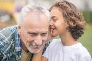 Koyu saçlı tatlı çocuk babasıyla sırlarını paylaşıyor.