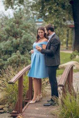 Doğada köprüde duran kadın ve erkek.