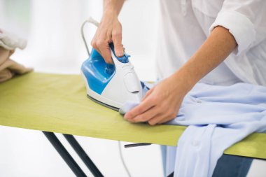 Kadın ellerinin gömleği ütülediği resmi kapat.