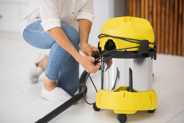 Woman crouched near vacuum cleaner without face