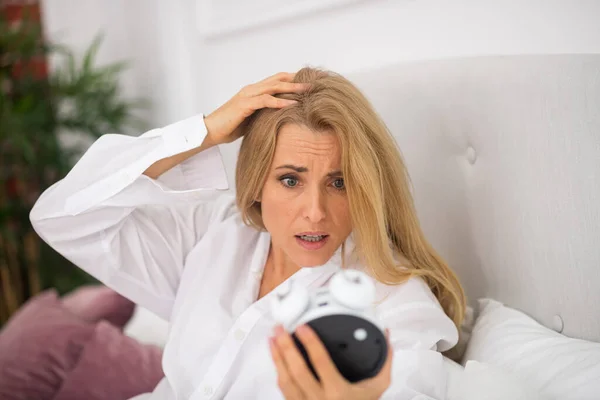 Woman looking with horror at alarm clock — Stock Photo, Image