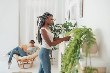 Afro-Amerikalı kız odayı temizliyor ve pozitif görünüyor.