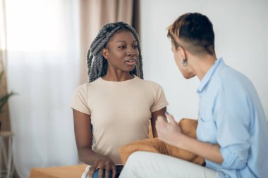 İki kız yan yana oturuyor ve güzel güzel sohbet ediyorlar.