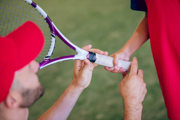 Coach in a red cap and a boy with a tennis racket
