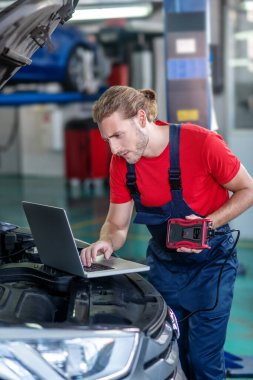 Arabanın yanında bilgisayarı olan ilginç bir tamirci.