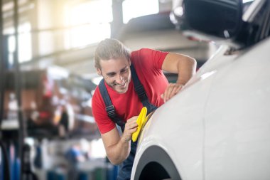 Özel peçeteyle araba cilalayan enerjik tamirci.