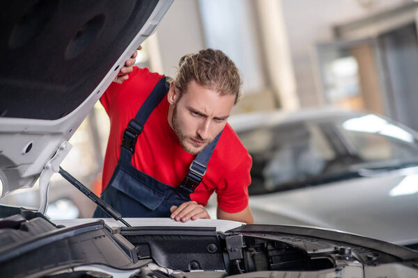 Repairman examining the insides of an open hood