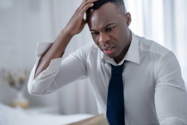 Zarif bir adam gazete okuyor ve üzgün görünüyor.