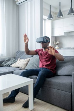 VR gözlüklü esmer tenli genç bir adam.